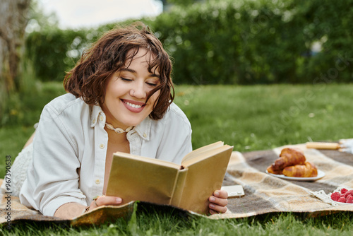 A young woman relaxes outdoors, immersed in a book while surrounded by a delightful picnic spread.