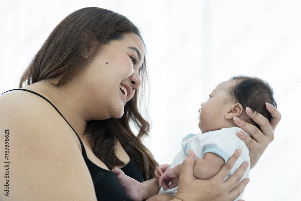 Asian plus size mother embracing and carrying her newborn baby at home Asian plus size mother embracing and carrying her newborn baby at home