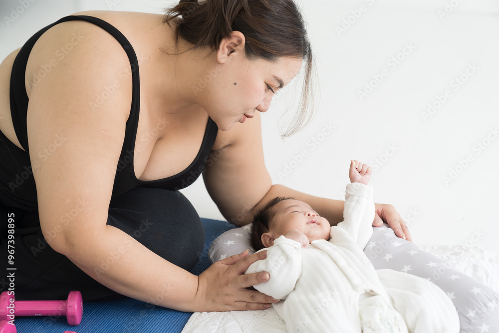 Asian plus size mother doing exercises on yoga mat and taking care her newborn at home Asian plus size mother doing exercises on yoga mat and taking care her newborn at home