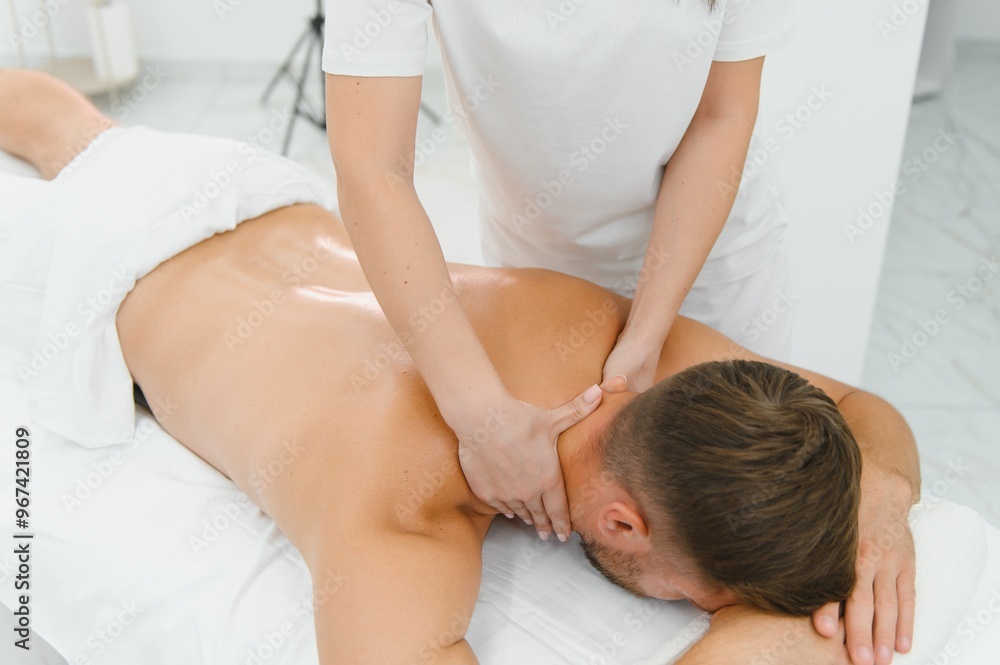 Young man having a massage by a professional masseuse Young man having a massage by a professional masseuse