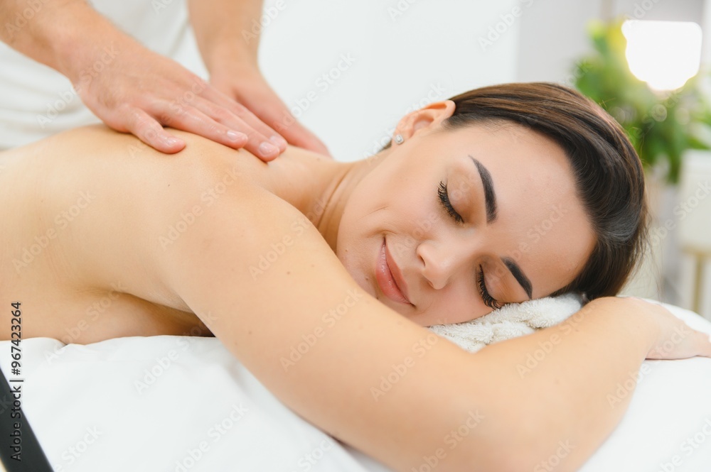 A young brunette woman receives a professional back massage in a spa salon. A beautiful naked lady in a towel with perfect skin gets a relaxing massage. The concept of luxury professional massage A young brunette woman receives a professional back massage in a spa salon. A beautiful naked lady in a towel with perfect skin gets a relaxing massage. The concept of luxury professional massage