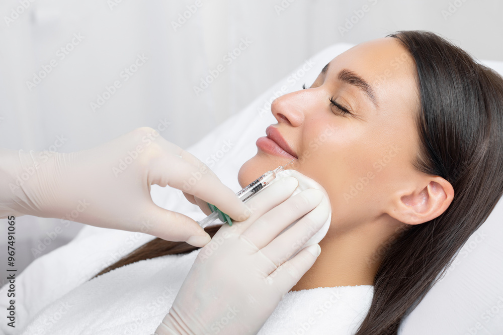 Cosmetologist making beauty injection to young woman, holding syringe near female lips, closeup shot Cosmetologist making beauty injection to young woman, holding syringe near female lips, closeup shot