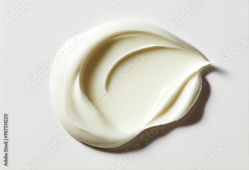 A dollop of thick, creamy white skincare cream on a muted white background. Cream looks like it's been squeezed onto a surface. The cream is sheen reflecting light