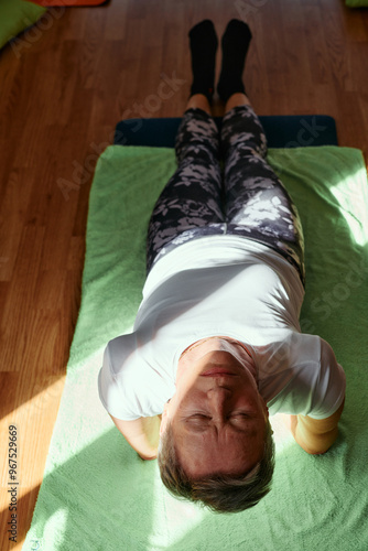 Senior woman practicing stretching and meditation on the floor, focusing on proper alignment and relaxation. photo