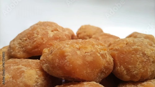 Micro shot of Jaggery or Gur pieces rotating on white background. Organic brown cane sugar pieces photo