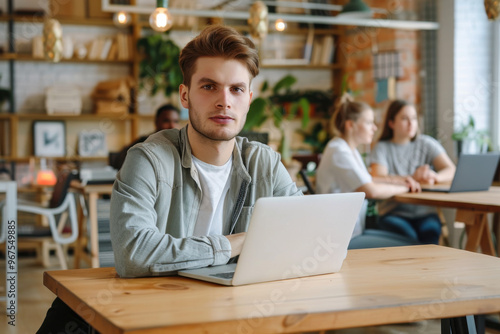 Portrait of a stylish male student working on his university exercise on a laptop computer. Young handsome man studying an online college course in an quiet public library