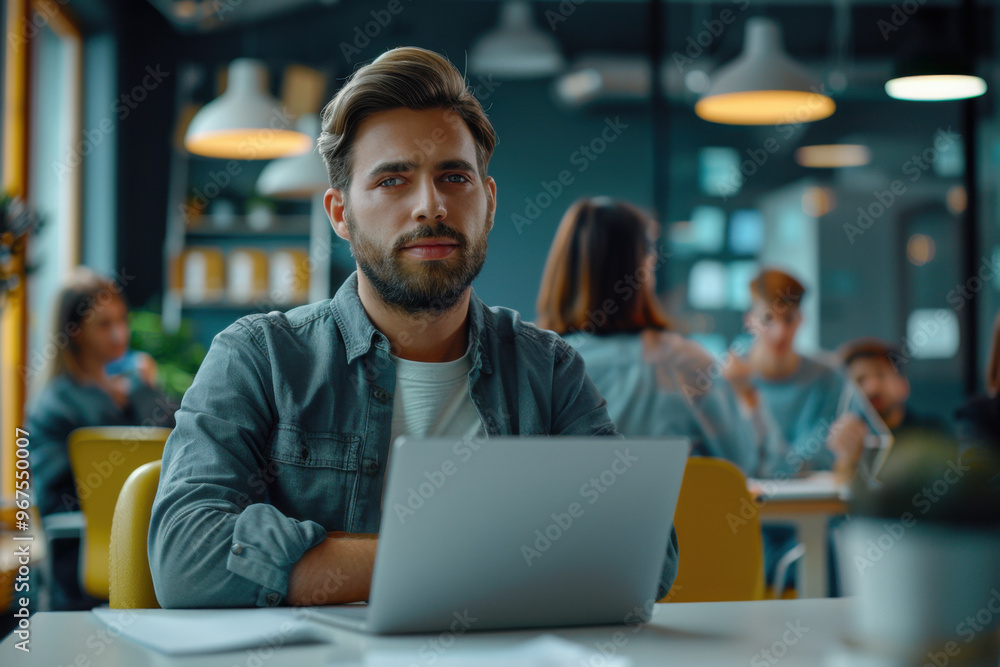 Portrait of a business man sitting in an office with his colleagues in the background. Happy business man working in a co-working office. Portrait of a business man sitting in an office with his colleagues in the background. Happy business man working in a co-working office.