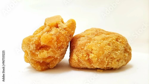 Pieces of Jaggery or Gur isolated rotating on white background, micro shot. Organic brown cane sugar piece isolated photo