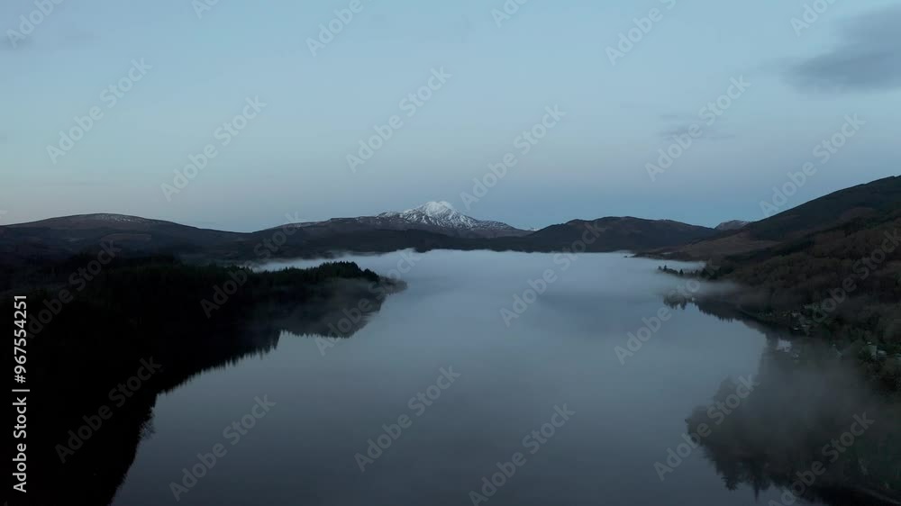 Aerial view of tranquil Loch Ard surrounded by majestic mountains and serene fog, Aberlour, United Kingdom. Aerial view of tranquil Loch Ard surrounded by majestic mountains and serene fog, Aberlour, United Kingdom.