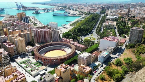 Drone flight over the city center of Malaga (Spain), bullfighting arena, port, sea, townhall and residential sector. Sunny weather, day view.