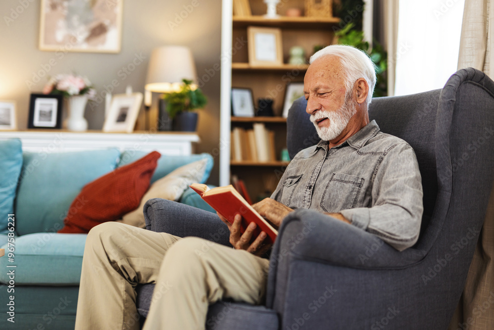 Senior man enjoys reading book alone in the living room. Old man alone at home. Senior man enjoys reading book alone in the living room. Old man alone at home.