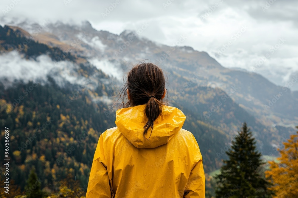 Observing the valley and mountains from the top of a hill in a yellow raincoat Observing the valley and mountains from the top of a hill in a yellow raincoat