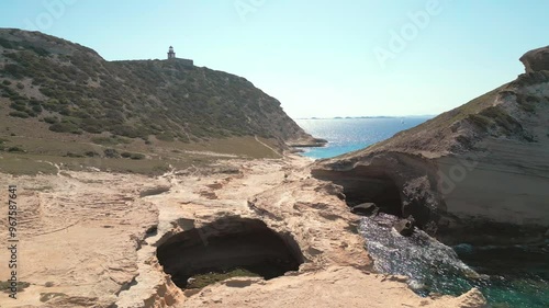 Aerial view panning across the Grotte de Saint Antoine, Capo Pertusato, the Gouvernail de la Corse and Plage de Saint Antoine near Bonifacio on the Mediterranean island of Corsica photo