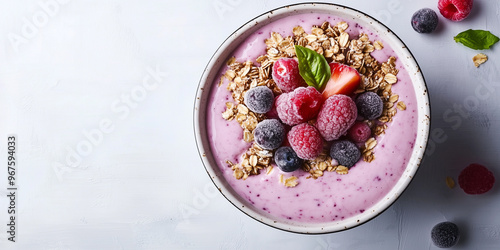 Fruit smoothie bowl topped with granola and frozen fruit pieces