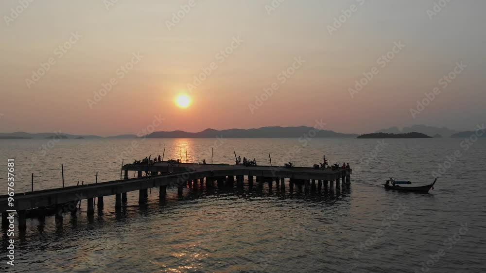 Aerial view of serene sunset over a tranquil sea with a pier and boats, Ko Yao Noi, Thailand. Aerial view of serene sunset over a tranquil sea with a pier and boats, Ko Yao Noi, Thailand.