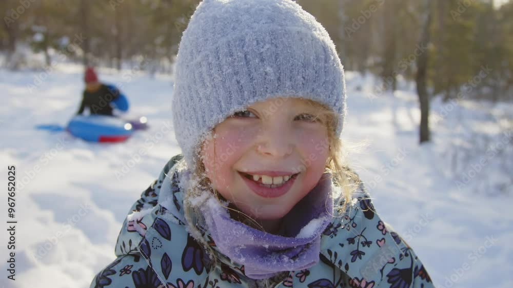 Closeup portrait of adorable cheerful 8-year-old Caucasian girl posing in warm clothes covered in snow in winter park after playing with friends and looking at camera Closeup portrait of adorable cheerful 8-year-old Caucasian girl posing in warm clothes covered in snow in winter park after playing with friends and looking at camera