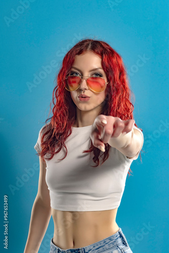 Portrait of a young woman with long red wavy hair pointing on yo photo