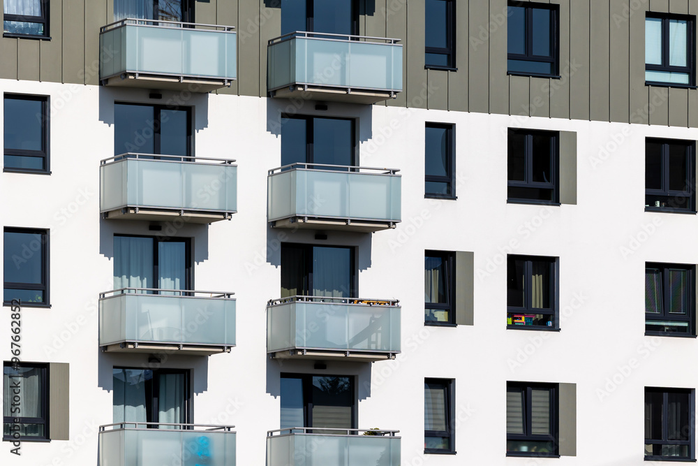 White and beige facade of a newly built apartment block. Clear blue sky above the building. Photo taken on a sunny day
