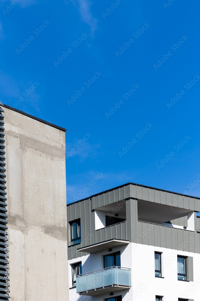 White and beige facade of a newly built apartment block. Clear blue sky above the building. Photo taken on a sunny day