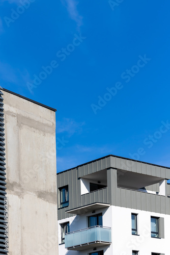 Obraz na płótnie White and beige facade of a newly built apartment block. Clear blue sky above the building. Photo taken on a sunny day w salonie