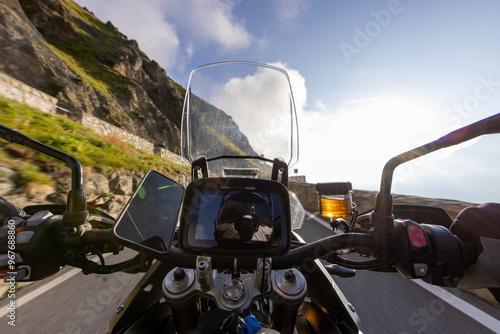 Motorbiker riding in Italian Alps during sunrise, dramatic sky. Travel and freedom, outdoor activities