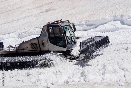 The snow tractor snowcat, snow groomer is ready for work, confidently standing against the backdrop of a snowy landscape, embodying power and reliability in winter conditions photo