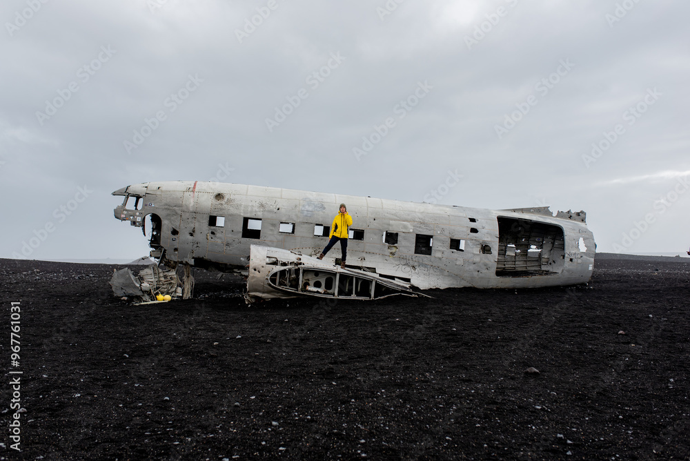 Abandoned plane crash with a man standing on it on a black volcanic beach Abandoned plane crash with a man standing on it on a black volcanic beach