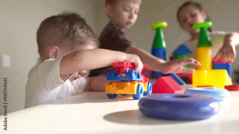 kids girl and baby boy play in kindergarten. a group of children indoor play toys cubes and cars on the table in kindergarten. happy family preschool education concept. nursery baby toddler home kids girl and baby boy play in kindergarten. a group of children indoor play toys cubes and cars on the table in kindergarten. happy family preschool education concept. nursery baby toddler home