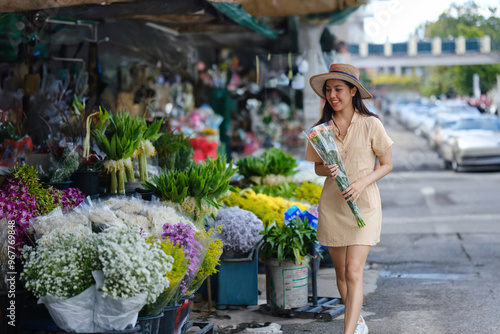 A woman is walking down a street with a bouquet of flowers in her hand