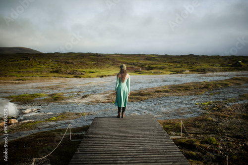 Serene Woman in Green Dress Standing by Steam in Nature