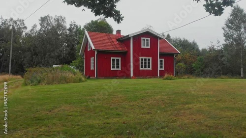 Aerial view of a picturesque red wooden house surrounded by tranquil greenery and trees in the countryside, Ljungby, Sweden. photo