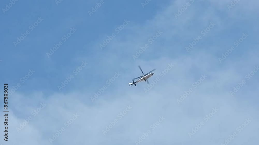 Helicopter in flight against background of blue sky and white clouds on sunny weather - slow moltion. Topics: air transport, travel, weather Helicopter in flight against background of blue sky and white clouds on sunny weather - slow moltion. Topics: air transport, travel, weather