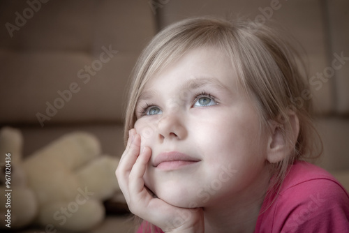 Sad little girl feels lonely laying on a floor and looking in window