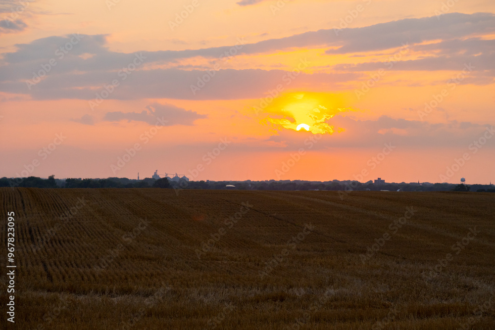 Farm fields with silo and grain elevator on the horizon at sunset in South Dakota Farm fields with silo and grain elevator on the horizon at sunset in South Dakota