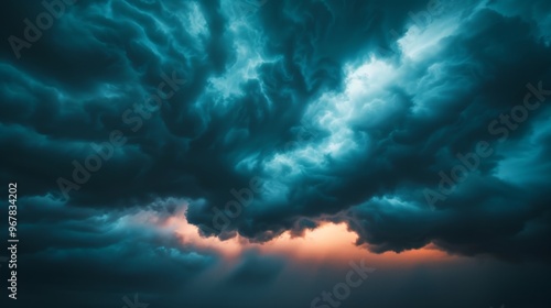 A dramatic sky filled with dark, swirling clouds, with a sliver of warm light breaking through the bottom. photo