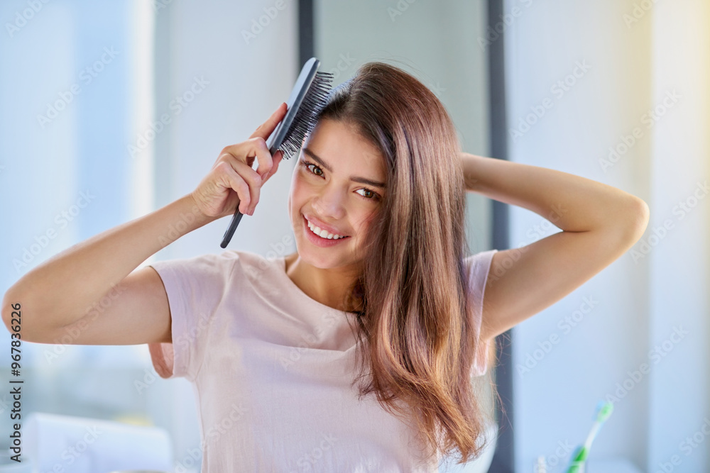 Fototapeta premium Woman, portrait and brushing hair in home, grooming and morning for getting ready in bathroom. Female person, cosmetics tool and hairbrush for hairstyle, Indonesia and treatment for healthy growth