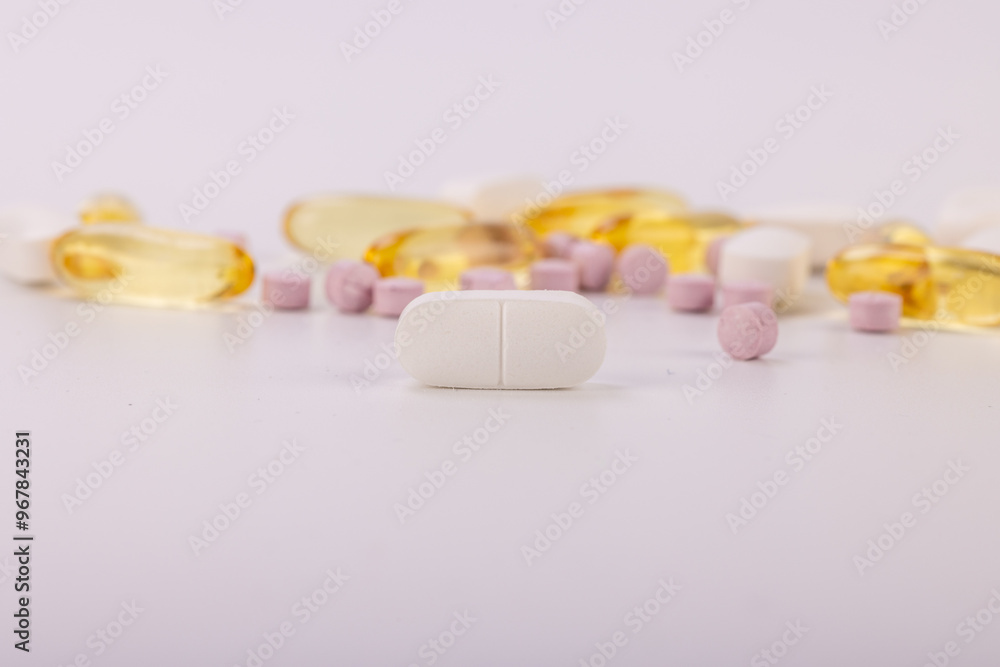 Colorful pills with a white one in focus on a white background Colorful pills with a white one in focus on a white background
