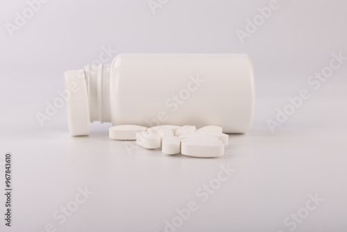 White Plastic Bottle Spilled With White Pills on Clean White Background