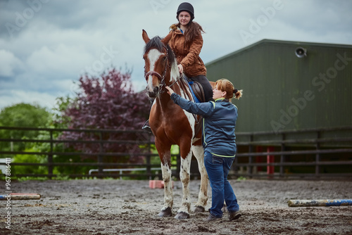 Horse, child and trainer on farm for riding sport, countryside training and equestrian development. Stallion, girl and woman for balance support, practise advice and ranch hobby for exercise outdoor photo