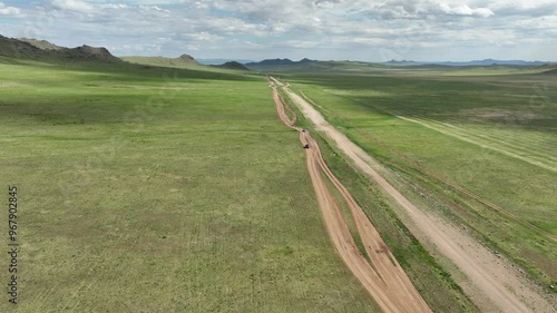 Aerial view of expansive green grassland and rugged mountains under a blue sky, Iven Valley, Mongolia. photo