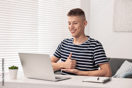 Young man using sign language during video call indoors