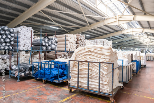 Fabric warehouse with lots of fabric rolls and stacks of fabrics in a textile factory.