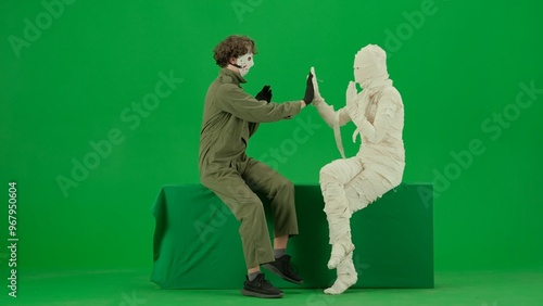 Fotografie Portrait of person in a mummy bandage on chroma key green screen background