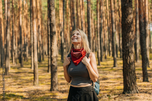 A young white woman tourist with a backpack in a pine forest in summer