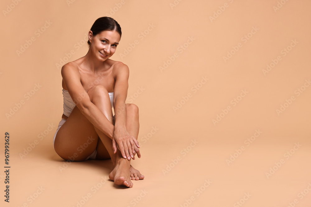 Smiling woman with perfect skin sitting on beige background, space for text. Body care Smiling woman with perfect skin sitting on beige background, space for text. Body care