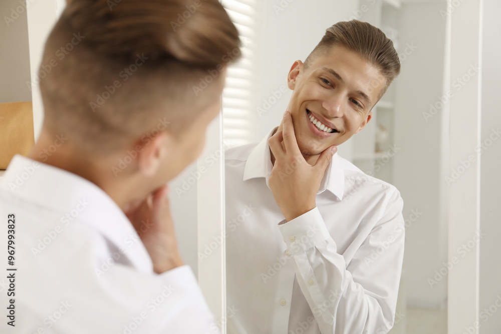 Fototapeta premium Handsome man in shirt looking at mirror indoors
