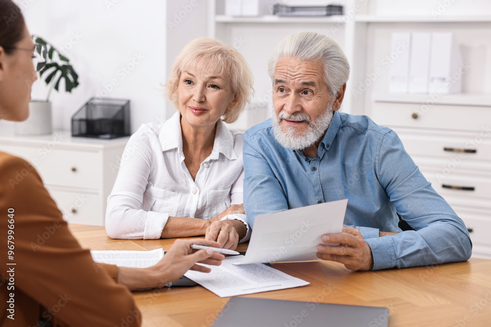 Pension plan. Senior couple consulting with insurance agent at wooden table indoors Pension plan. Senior couple consulting with insurance agent at wooden table indoors