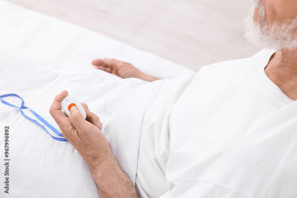 Senior man pressing emergency call button on bed in hospital, closeup Senior man pressing emergency call button on bed in hospital, closeup