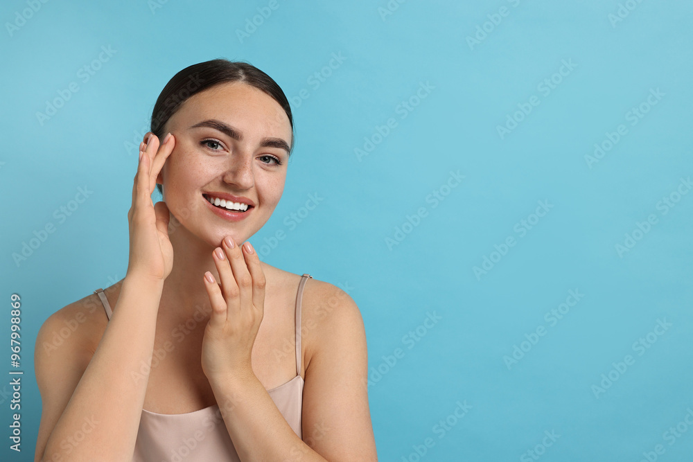 Face massage. Beautiful young woman with healthy skin on light blue background, space for text Face massage. Beautiful young woman with healthy skin on light blue background, space for text