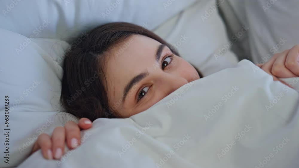 Playful woman peeking bed closeup. Cute beautiful brunette hiding under blanket Playful woman peeking bed closeup. Cute beautiful brunette hiding under blanket